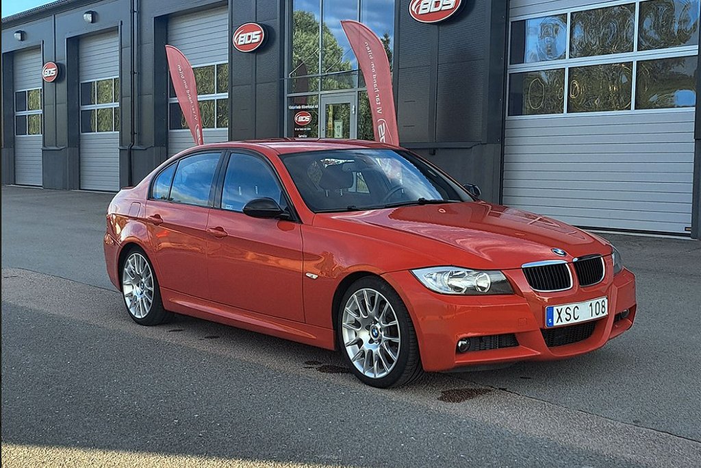 Röd BMW parkerad framför en verkstad med BDS-skyltar.