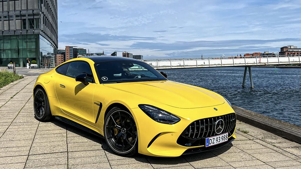 Gul Mercedes-AMG GT på en kaj bredvid vattnet.