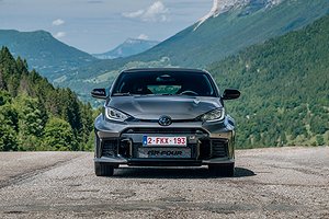 Toyota GR Yaris sedd framifrån på en landsväg med berg i bakgrunden.