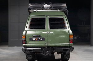Mörkgrön SUV, sedd bakifrån med ett takmonterat tält och två bakdörrar.