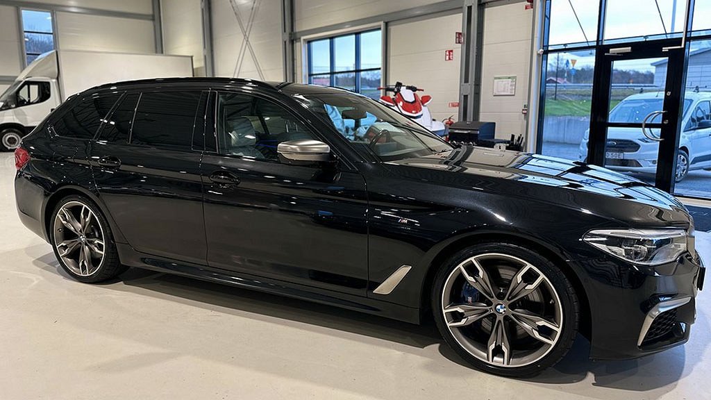 Sidovy av den svarta BMW:n i bilhallen, med sportig och elegant profil.