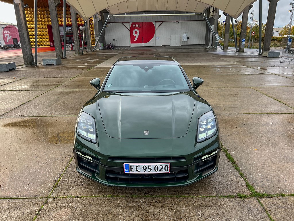 Grön Porsche Panamera rakt framifrån, parkerad på betongplattor.