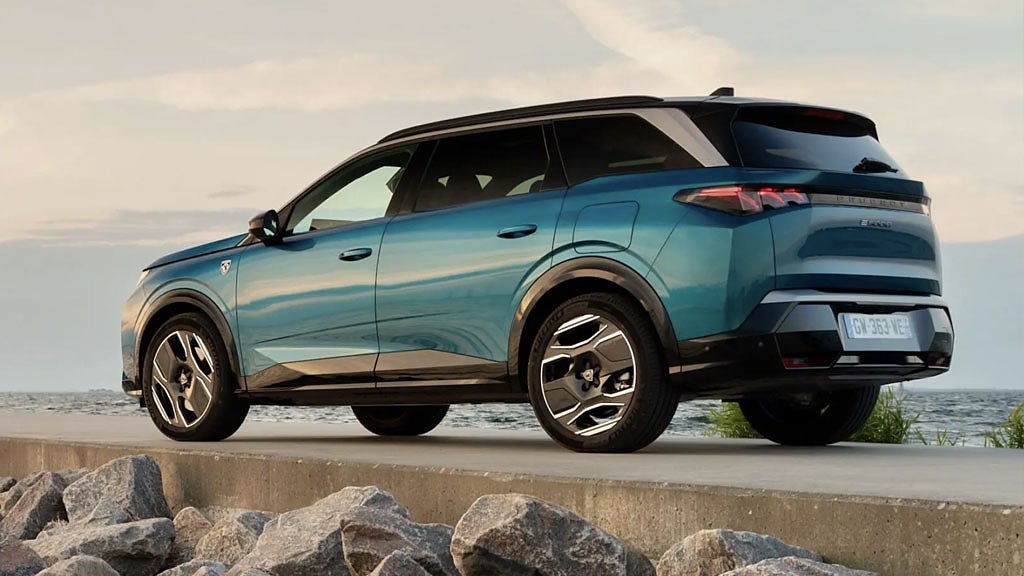 Mörkblå Peugeot SUV på en väg med havet i bakgrunden.