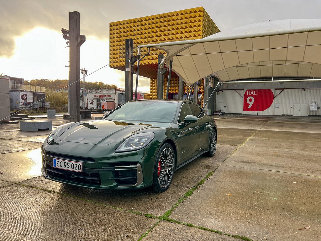 Grön Porsche Panamera framifrån snett, parkerad på betongplattor.