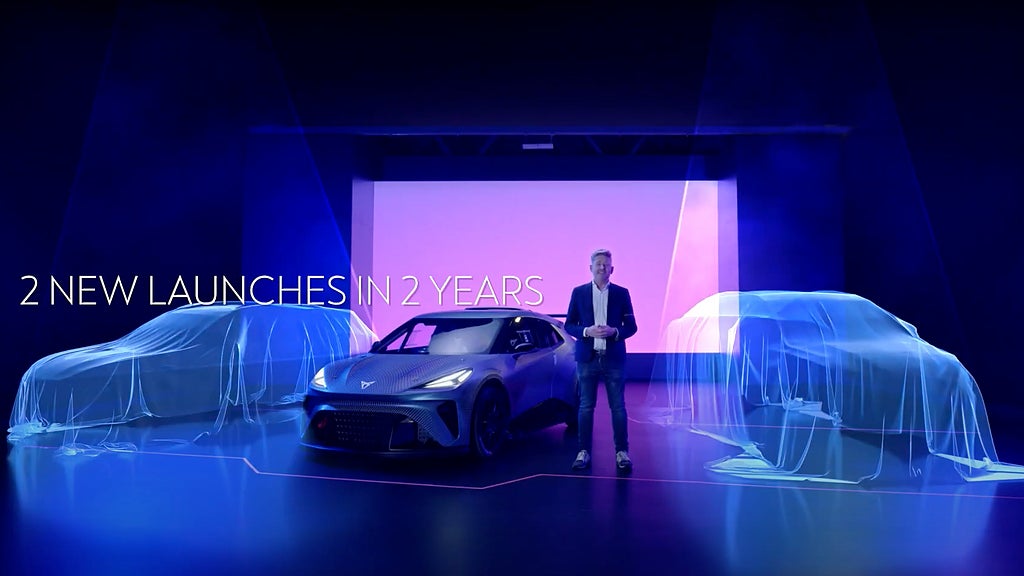 Cupras vd, Wayne Griffiths, visar Cupra Tavascan och UrbanRebel under ett skynke