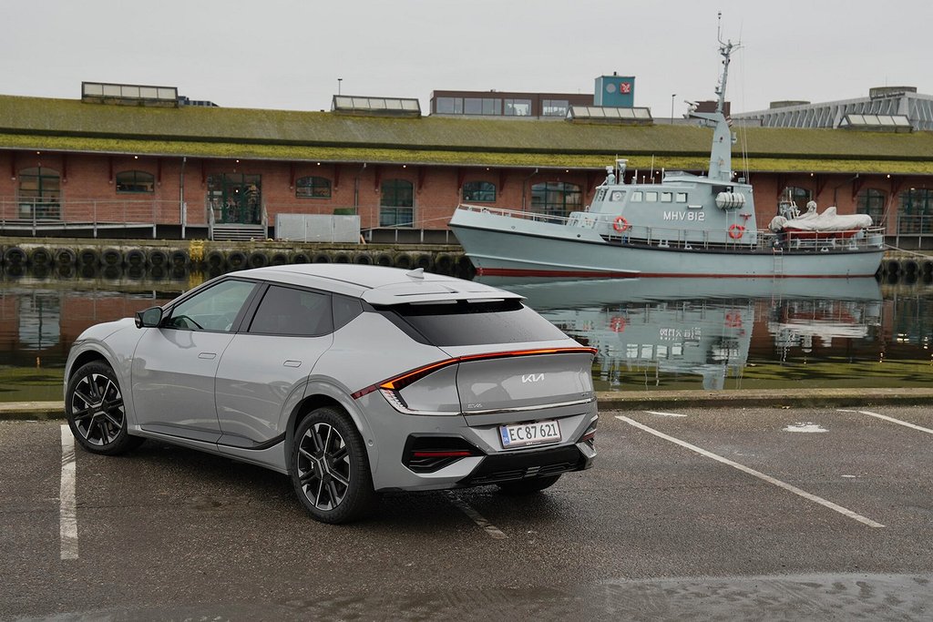 Kia EV6 parkerad vid en hamn med ett fartyg i bakgrunden.