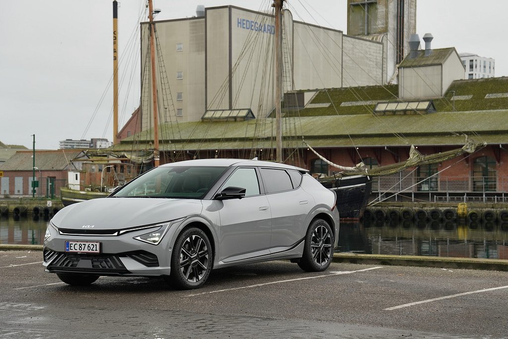 Kia EV6 parkerad framför en byggnad med segelfartyg i bakgrunden.